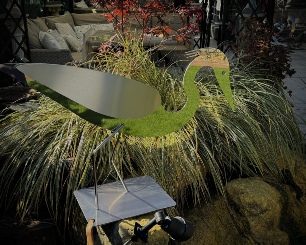 Stainless steel sculpture called "Poised to Strike" - a stylised grey heron bent over ready to catch its prey